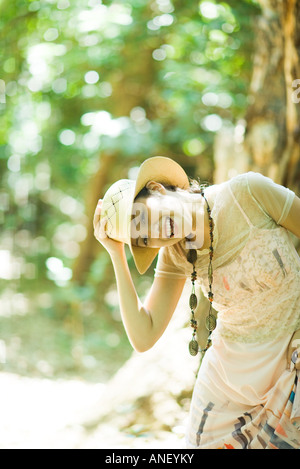 Junge Frau im Wald stehen, halten Hut am Kopf Stockfoto