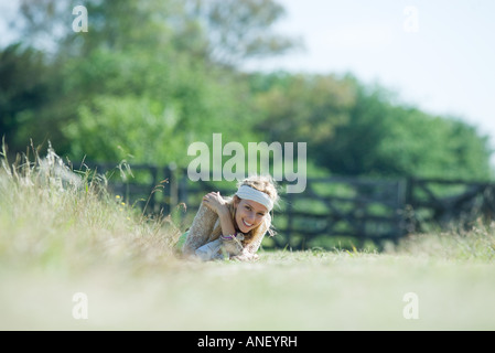 Junge Frau im Feld, liegend in die Kamera Lächeln Stockfoto