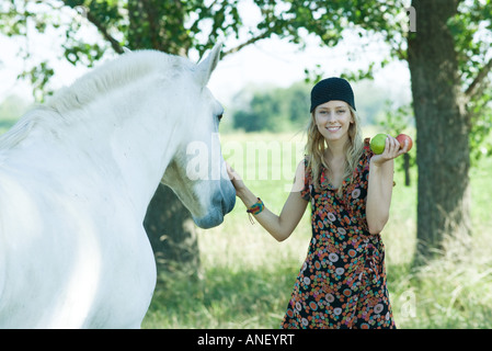 Junge Frau Petting Pferd, halten Äpfel in der hand Stockfoto