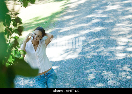 Lässig gekleidete Frau mit Handy im freien Hand hinter dem Kopf, erhöhte Ansicht Stockfoto