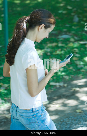 Frau zu Fuß durch den Park, Blick auf Handy Stockfoto