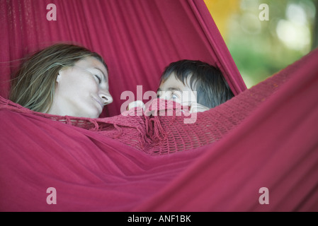 Mutter und Sohn liegen in der Hängematte, Frau schläft, junge Frau einsehen Stockfoto