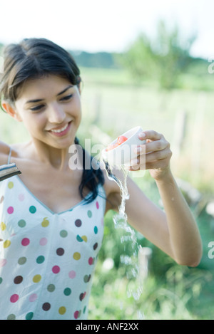 Junge Frau abspülen Tomaten mit Tasse im freien Stockfoto