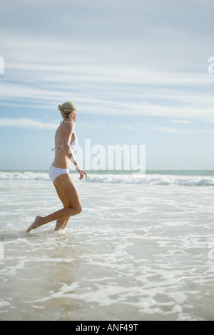 Junge Frau im Bikini, ausgeführt in surf Stockfoto