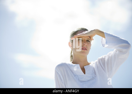 Junge Frau Schattierung Augen in Sonne, niedrigen Winkel Ansicht Stockfoto