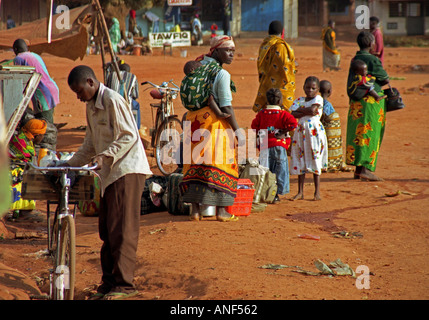 Mütter & Kinder in bunten Trachten warten Bushaltestelle beschäftigt Dorf Haupt Platz Korogwe Tansania Ostafrika Stockfoto