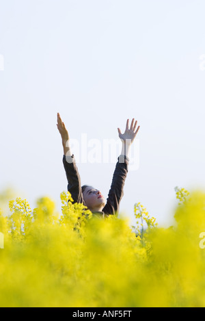 Mädchen stehen im Feld mit Armen angehoben, in Himmel Stockfoto