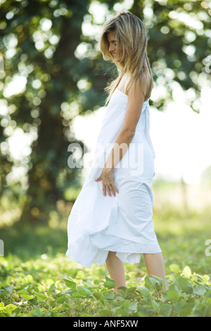 Junge Frau, die zu Fuß durch Feld, seitliche Ansicht Stockfoto
