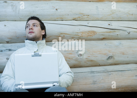 Junger Mann gekleidet in Winterkleidung, mit laptop Stockfoto