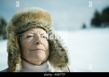 Ältere Frau, die in verschneiter Landschaft, Augen geschlossen, lächelnd, Kopf und Schultern Stockfoto