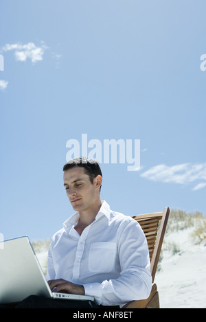 Geschäftsmann, sitzen im Liegestuhl am Strand, mit laptop Stockfoto