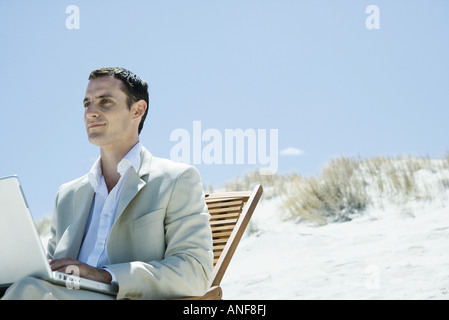 Geschäftsmann, sitzen im Liegestuhl am Strand, mit laptop Stockfoto