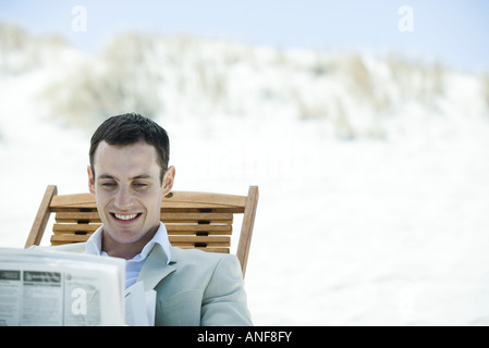 Geschäftsmann, sitzen im Liegestuhl am Strand, lesen Zeitung, Lächeln Stockfoto