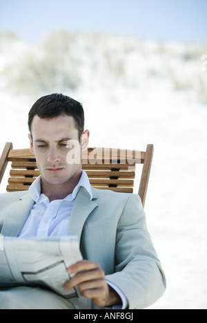 Geschäftsmann, sitzen im Liegestuhl am Strand, lesen Zeitung Stockfoto