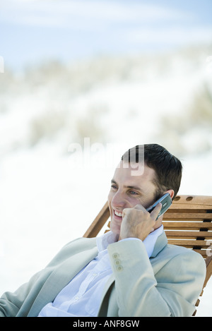 Geschäftsmann, sitzen im Liegestuhl am Strand, mit Handy Stockfoto