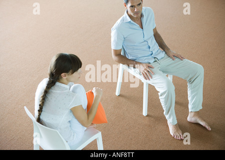 Mann und Frau sitzen auf Stühlen, wegsehen, erhöhte Ansicht Stockfoto