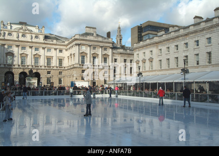 Erwachsene & Kinder Eisläufer mit Hintergrund historischen Somerset House Gebäude & Innenhof auf temporäre Winter Eislaufbahn Strand London, England, Großbritannien Stockfoto