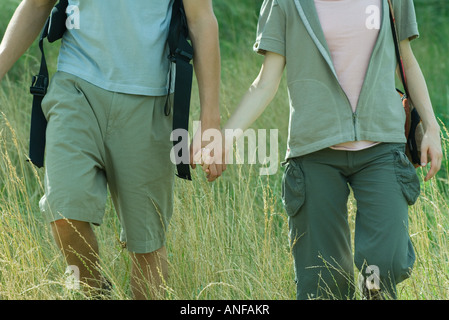 Junges Paar Wandern durch Feld, beschnitten Stockfoto