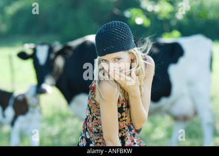 Junge Frau den Mund mit der Hand, Blick in die Kamera, Kühe im Hintergrund Stockfoto