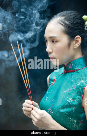Junge Frau trägt traditionellen chinesischen Kleidung, Weihrauch, Seitenansicht hochhalten Stockfoto