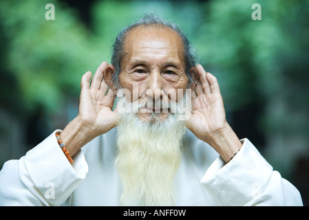 Älterer Mann Hand in Hand hinter Ohren Stockfoto
