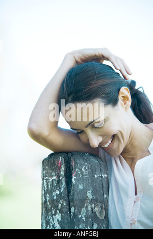 Frau, stützte sich auf Holzpfosten, lächelnd, Blick nach unten Stockfoto