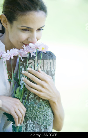 Frau stützte sich auf Holzpfosten, Blumen riechen Stockfoto