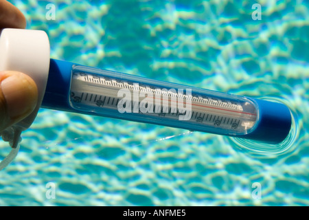 Tauchen einen Thermometer in einen pool Stockfoto