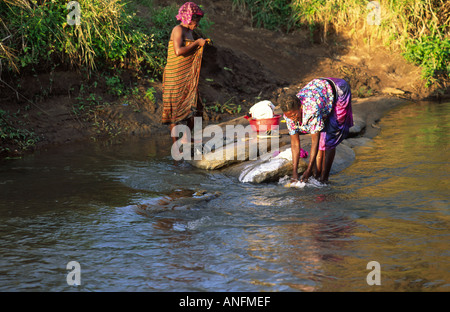 Ländliche Frauen waschen ihre Kleidung in den Fluss außerhalb ihres Dorfes in Zambezia Bezirk, Mosambik. Stockfoto