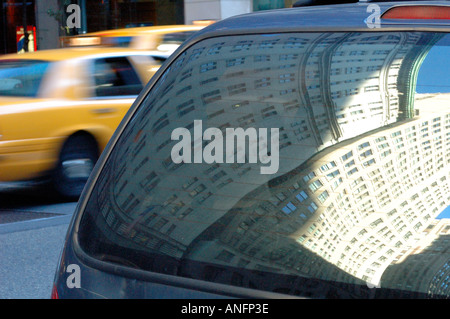 Ein Wolkenkratzer in der Heckscheibe eines Autos reflektiert, während ein verschwommenes yellow Cab Vergangenheit, New York, NY, USA zoomt Stockfoto