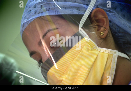 Asiatische Krankenschwester gekleidet in Scrubs arbeitet mit dem Rest des OP-Team UK Stockfoto