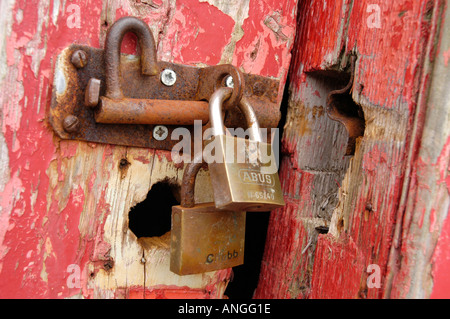 Zwei Vorhängeschlösser und Hasp und Grundnahrungsmittel, rot gemalte Hütte Tür zu sichern Stockfoto