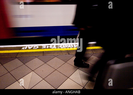 Pendler, die vorbei an Beschleunigung Rohr trainieren auf Londons u-Bahn-Netz mit Verstand die Lücke Zeichen auf Plattform lackiert Stockfoto