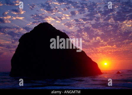 Die Sonne geht hinter Haystack Rock in Cannon Beach, Oregon, USA. Stockfoto
