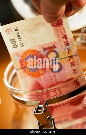 Nahaufnahme von Fingern mit chinesischen hundert Yuan-Banknote und Glas Vorratsgefäß Stockfoto
