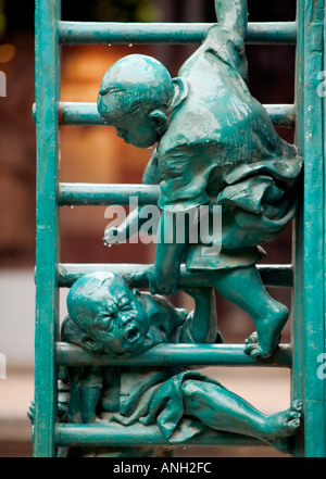 Ein grün Metall Statue von zwei Kinder spielen auf einer Leiter, mit ihren Kopf zwischen die Sprossen und der andere versucht zu helfen, Guangzhou, China blockiert Stockfoto