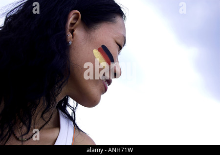 schöne chinesische Frau, die deutsche Flagge auf dem Gesicht malen Stockfoto