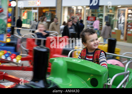 Kleiner Junge auf spannende Kreisverkehr fahren Weihnachts-Einkäufer und Fenster im Hintergrund anzeigen Stockfoto