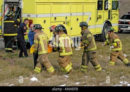Feuerwehrleute kümmern sich um verletzte Crash-Opfer eines Kopfes auf Automobil Absturz Stockfoto