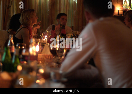 Leute sitzen herum und ein Candle-Light-Esstisch genießen Sie essen und trinken Stockfoto