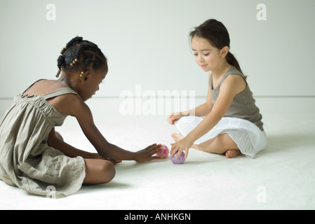 Zwei Mädchen sitzen auf dem Boden spielen mit Spielzeug-Kugeln Stockfoto