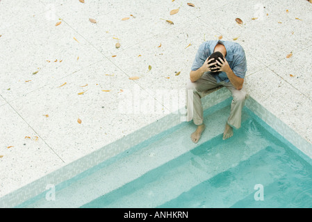 Mann, sitzend mit Füße im Pool, Kopf, hohen Winkel Ansicht Stockfoto