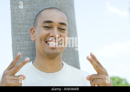 Mann, Peace-Zeichen geben und lächelt in die Kamera, Porträt Stockfoto