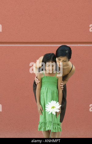 Frau und Mädchen stehen, Blick auf Blume Stockfoto