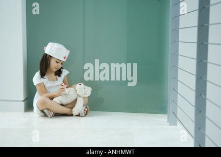Kleines Mädchen in Krankenschwester Hut geben Teddy Bär erschossen Stockfoto