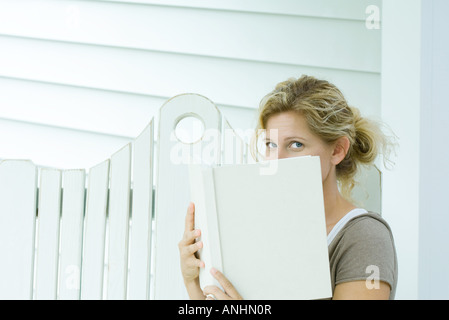 Frau über Buch in die Kamera schauen Stockfoto