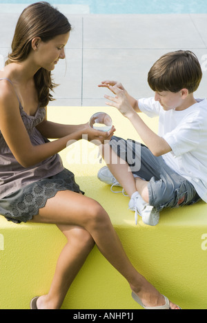 Teenager-Mädchen und jüngere Bruder sitzen, Blick in die Kristallkugel zusammen Stockfoto