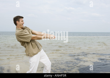 Mann spielen Tauziehen am Strand, Seitenansicht Stockfoto