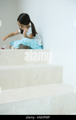 Mädchen sitzen auf Stufen spielen mit Top, niedrigen Winkel Ansicht Stockfoto