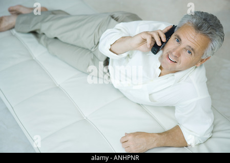 Reifer Mann liegend auf Chaise Longue mit schnurlosen Telefon Kamera blickte Stockfoto